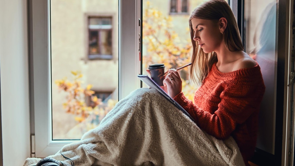 Personne assise près d’une fenêtre dans une ambiance douce, illustrant la reconstruction après un traumatisme.